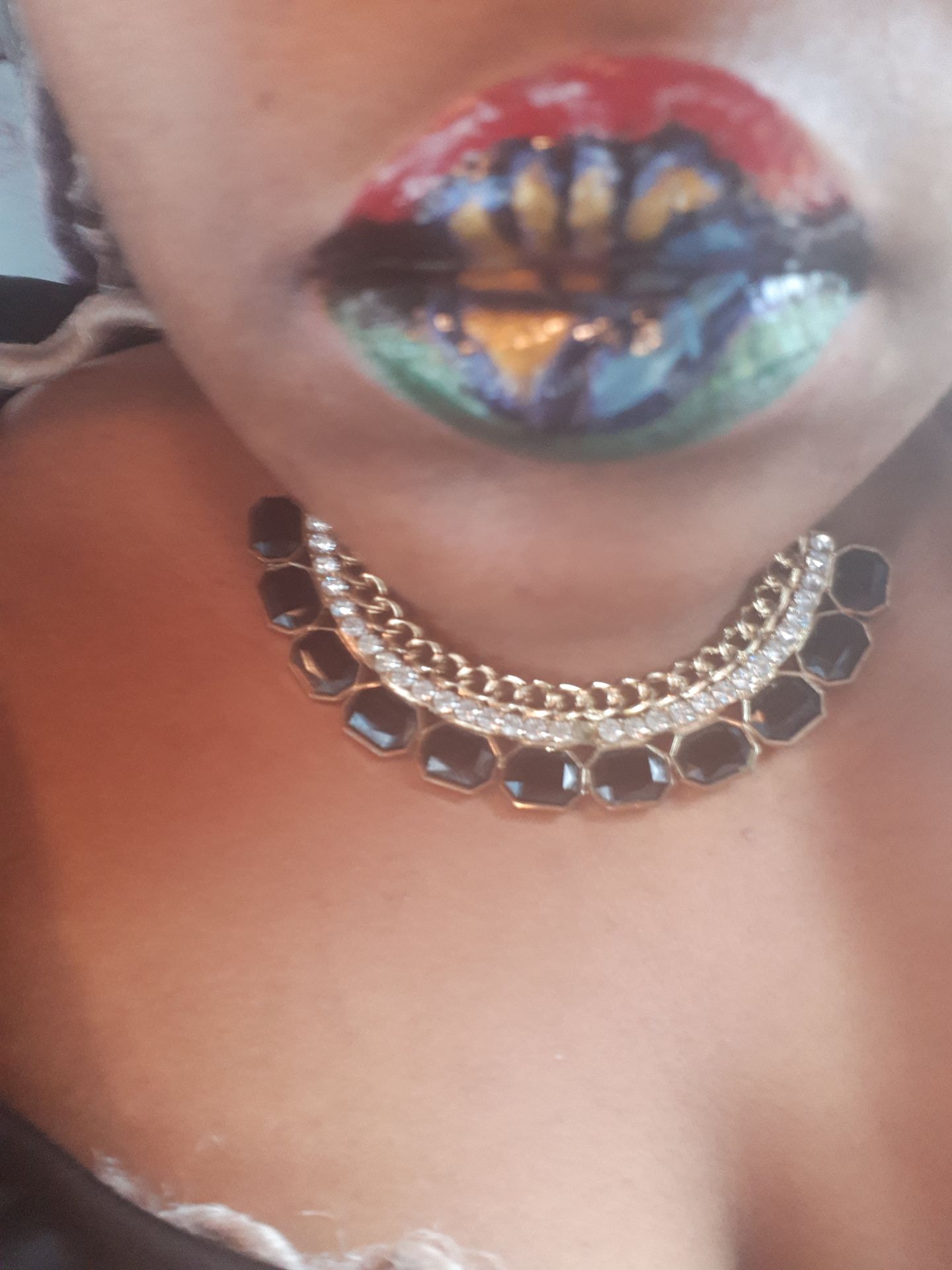 Close-up of multicolor jewel-studded lips with layered crystal choker