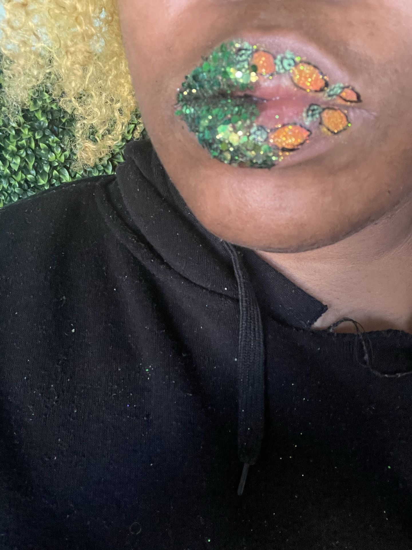 Close-up of green gemstone lip design against a black shirt