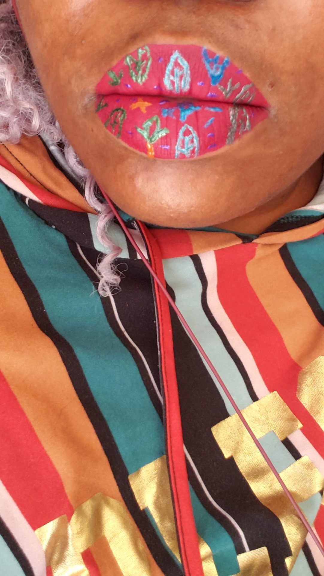 Close-up of red and teal geometric lip art with patterned fabric