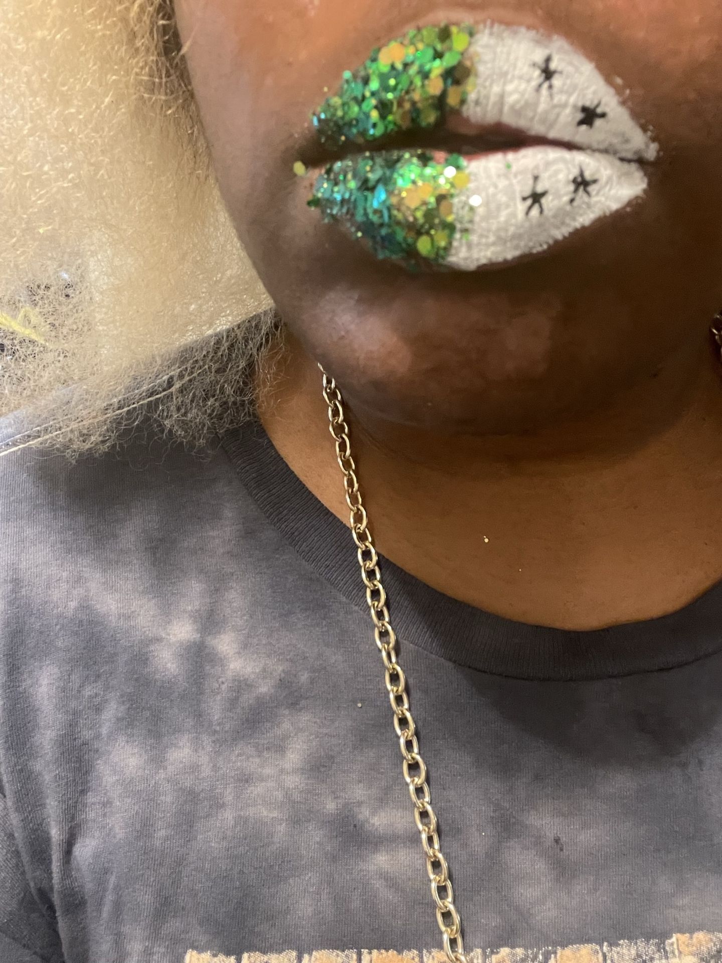 Close-up of metallic green and gold foil lips above a black top