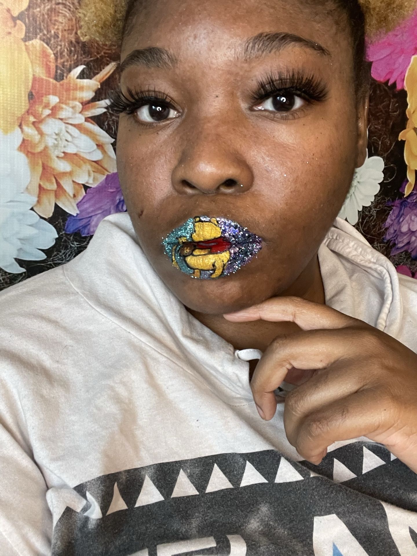 Woman with pastel blue hair touching her chin, wearing lime and gold crystal lip art