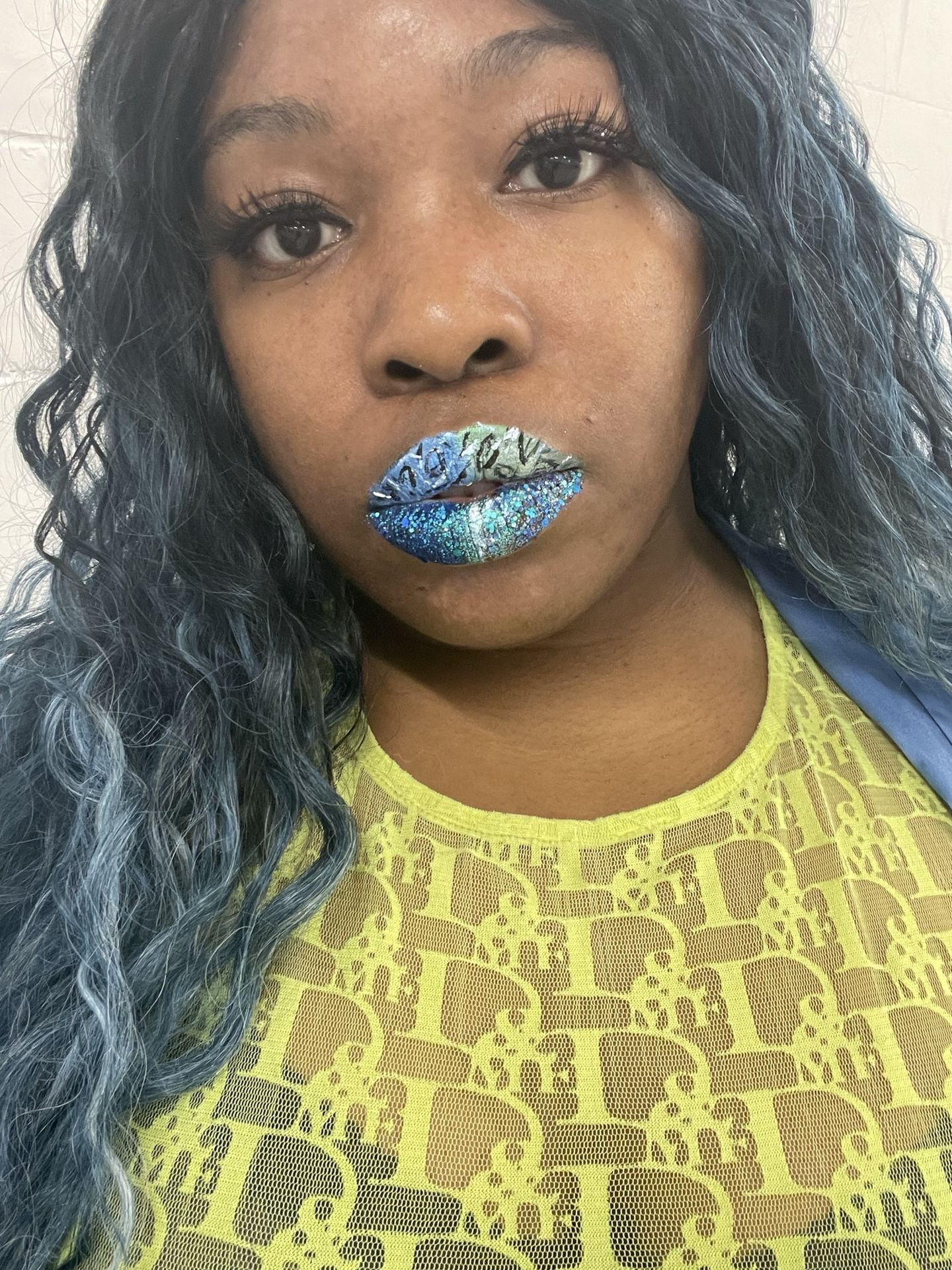 Black woman with metallic teal lipstick and yellow textured top