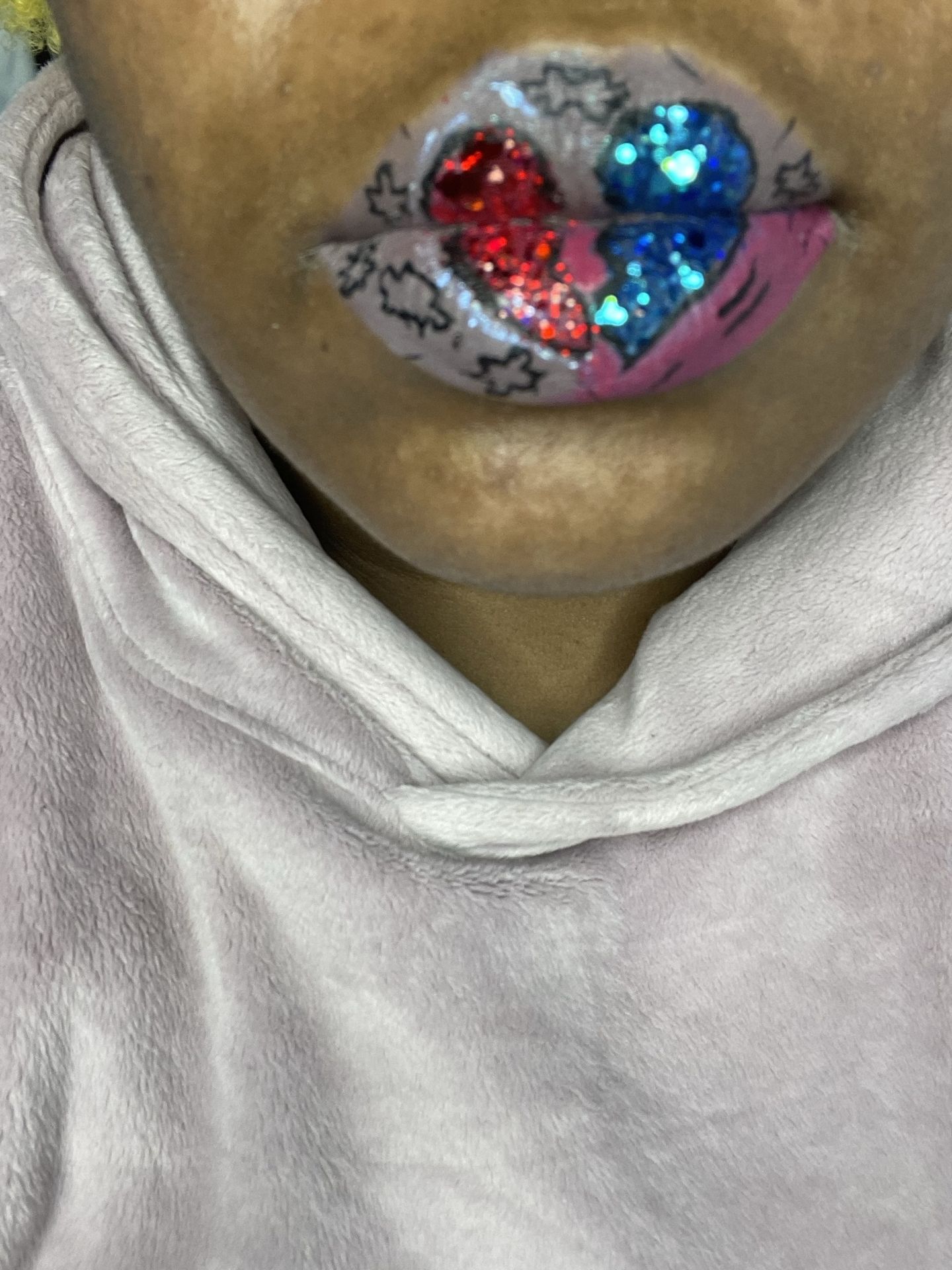 Close-up of red and silver crystal lip mosaic with beige hoodie