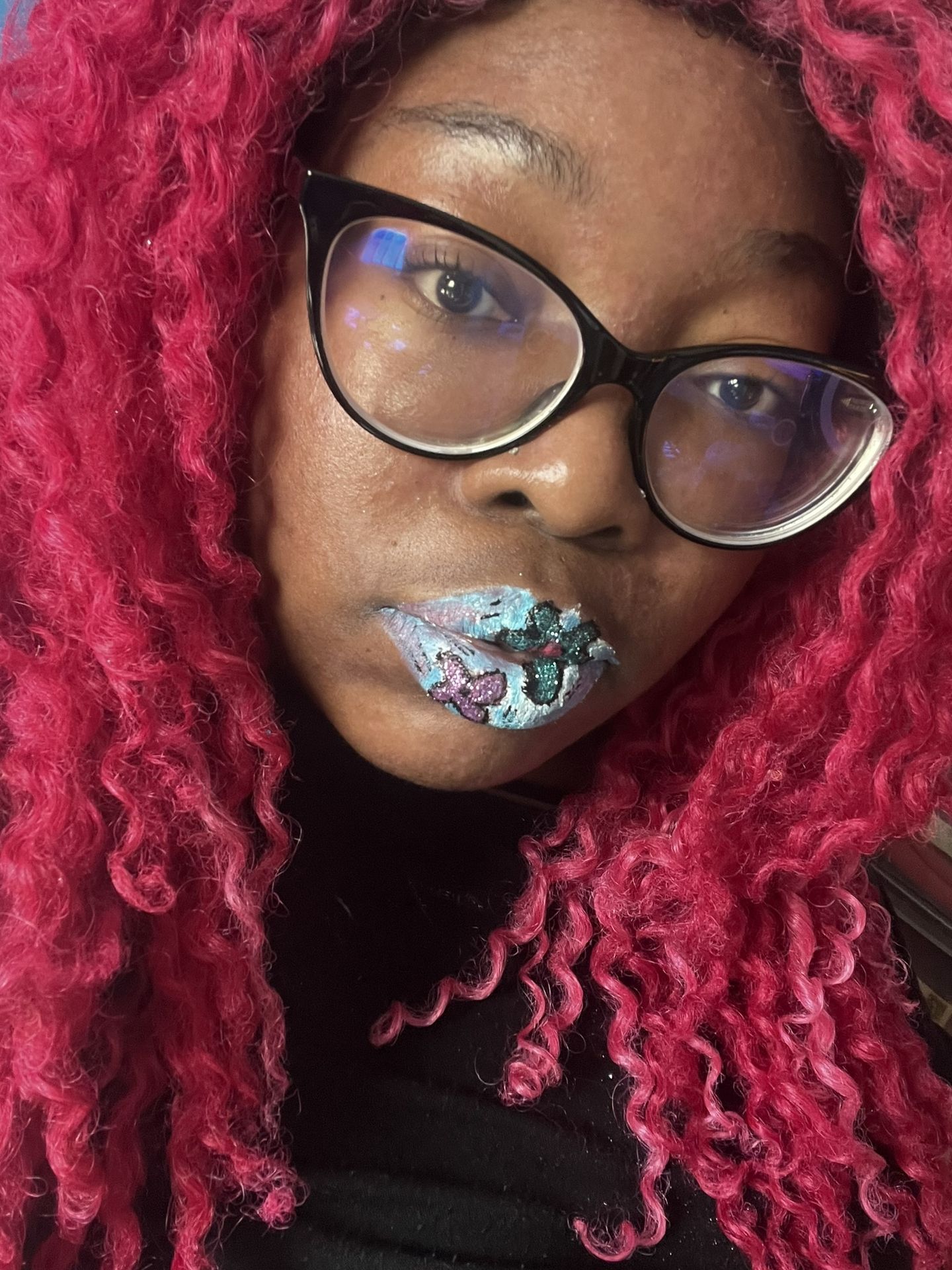 Woman with red curls and glasses wearing silver crystal lip art