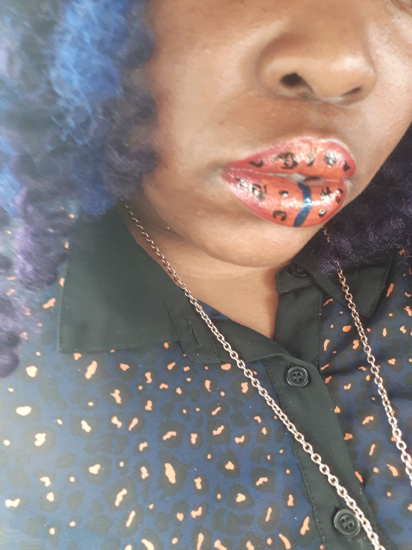 Woman in dark top wearing copper-orange glitter lips with scattered gems