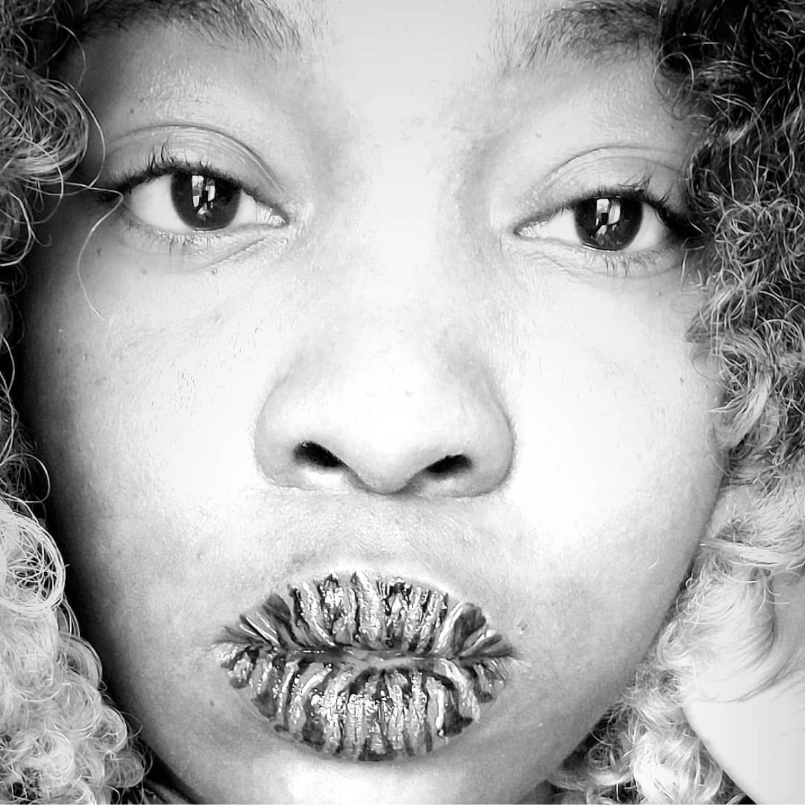 Black-and-white close-up of a woman with silver glitter covering her lips