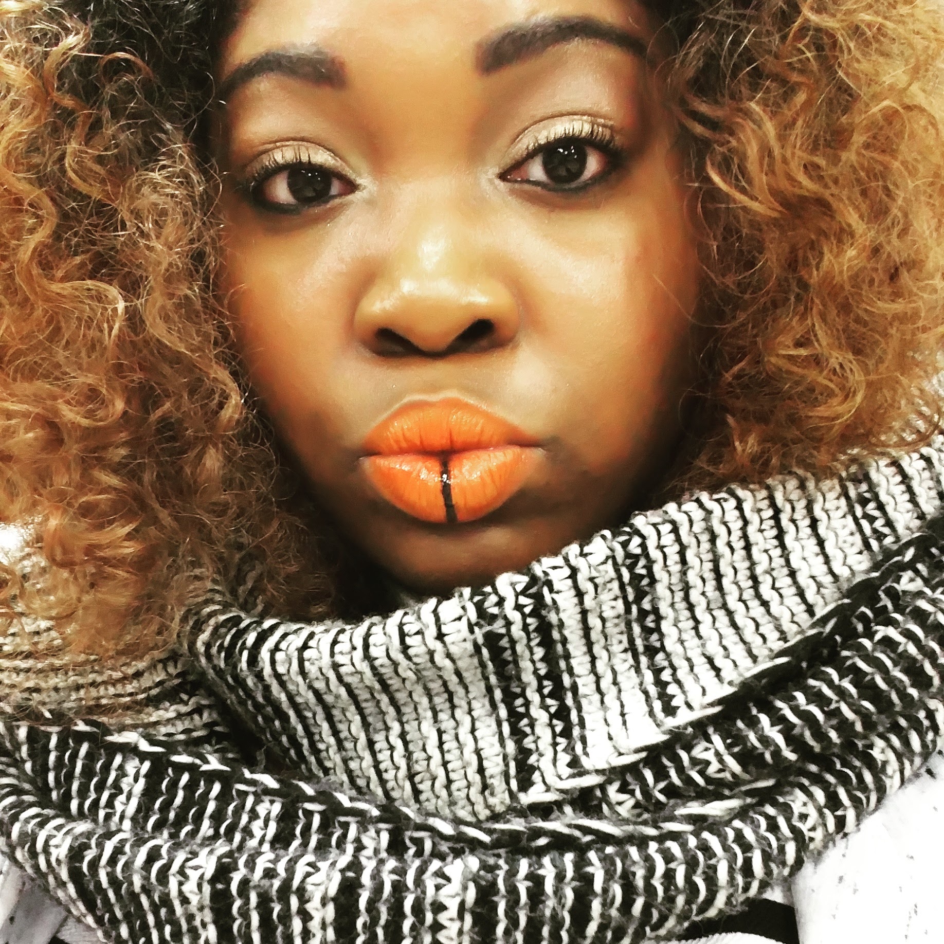 Woman with golden curls wearing bright orange matte lipstick