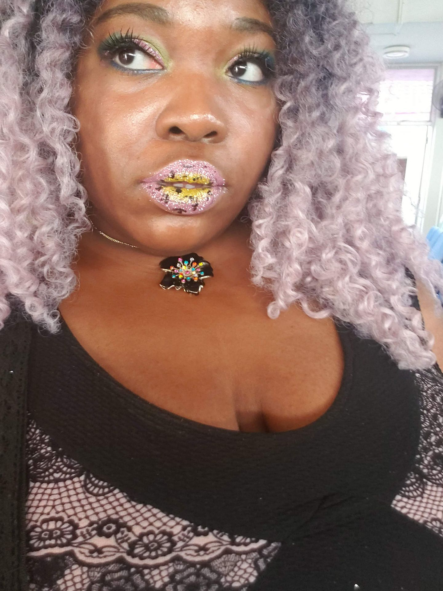 Woman with silver curls and deep plum lipstick, wearing a gold pendant