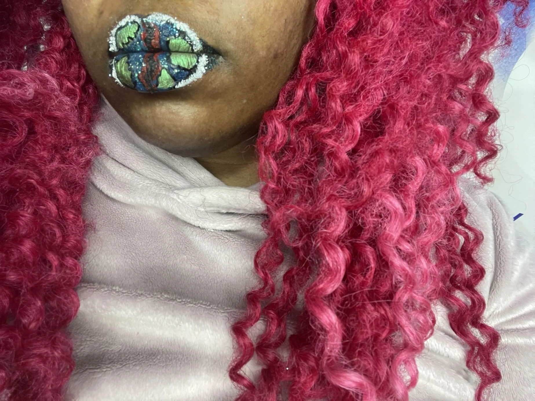 Close-up of iridescent gemstone lips framed by pink curls