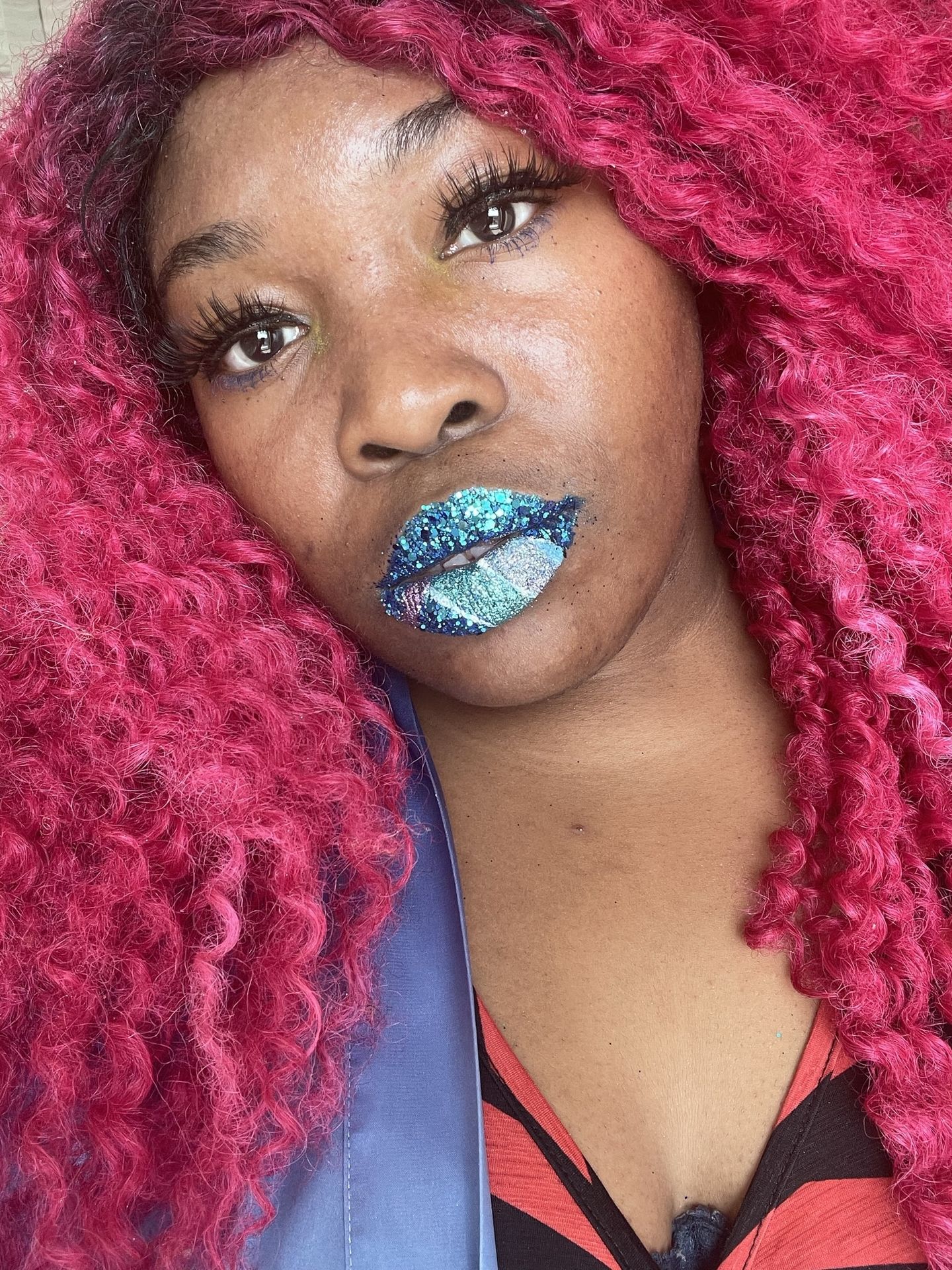 Black woman with pink braids and metallic blue lipstick