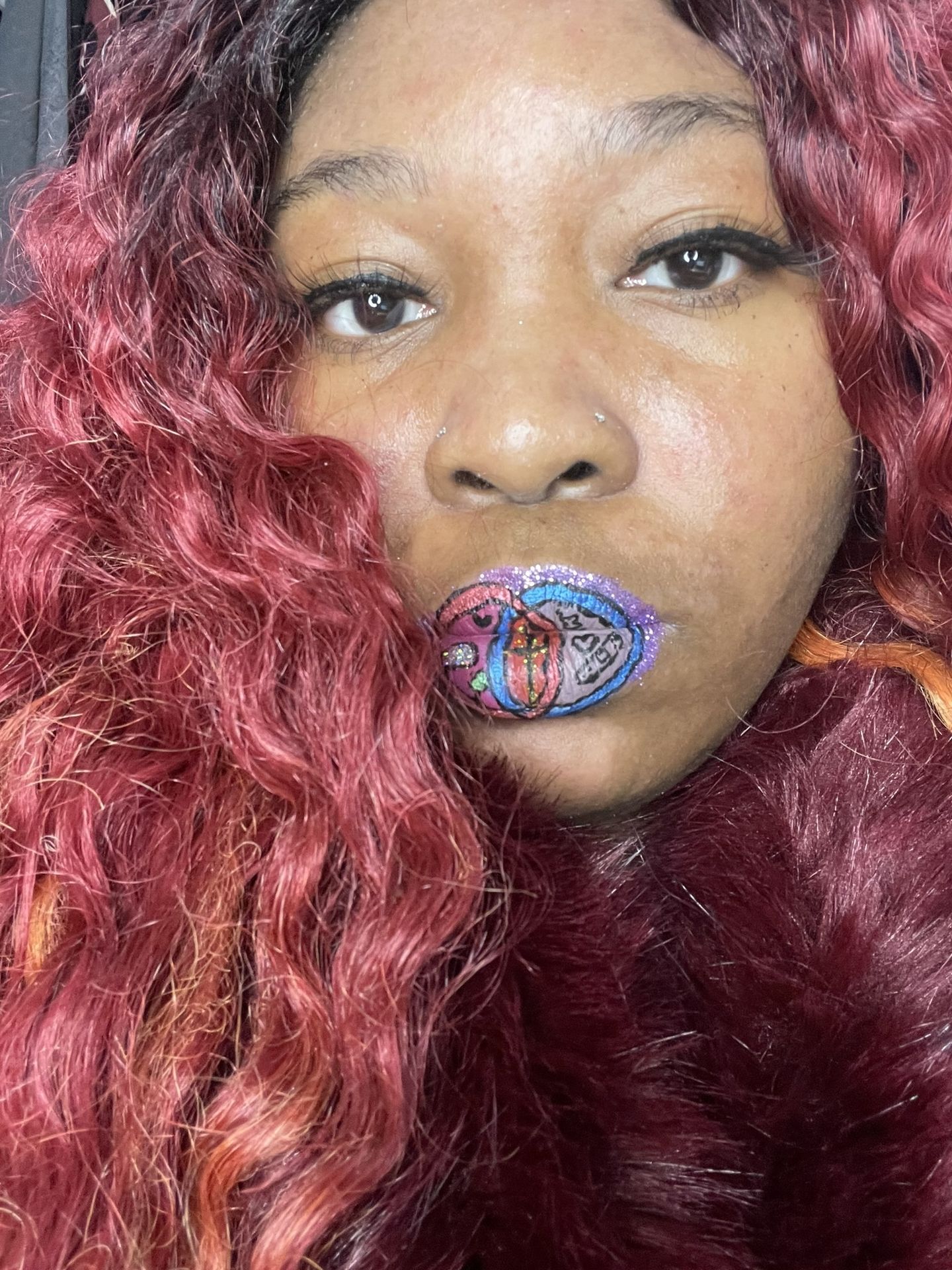 Woman with red curls wearing blue and gold crystal lip accents