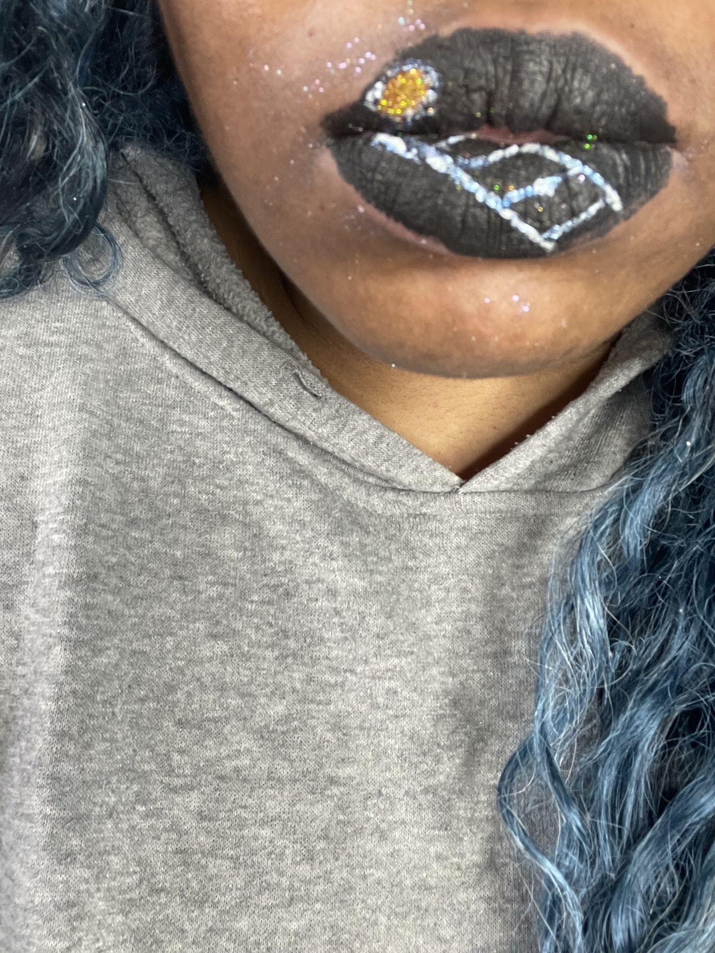 Close-up of silver and charcoal geometric lip art above a gray sweater