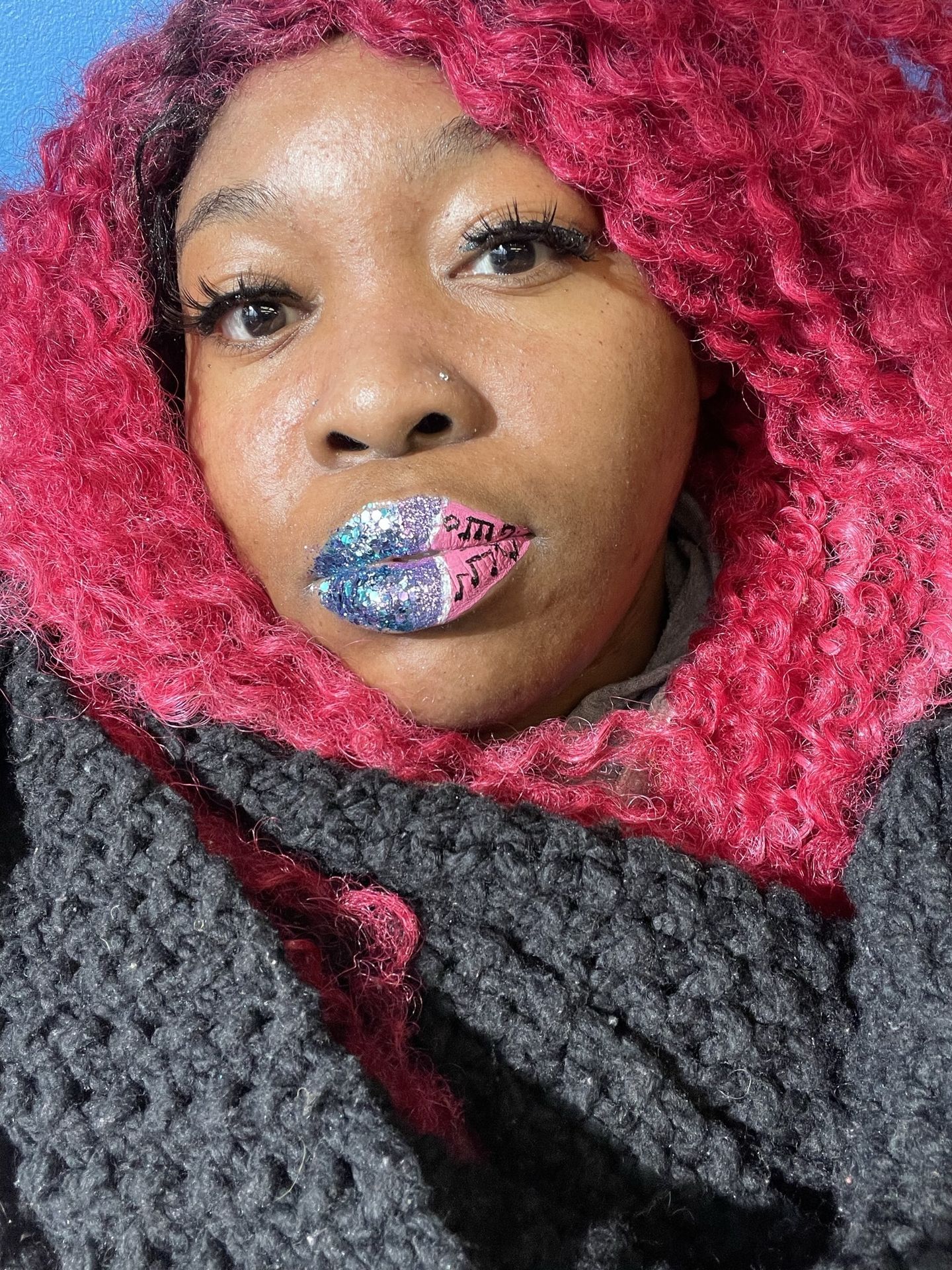 Black woman with red curls and green gemstone-style lip design, bold creative makeup photography.