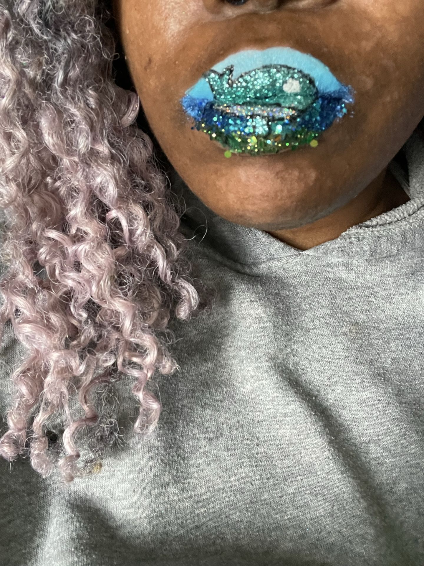 Close-up of green crystal lip design with silver textured sweater
