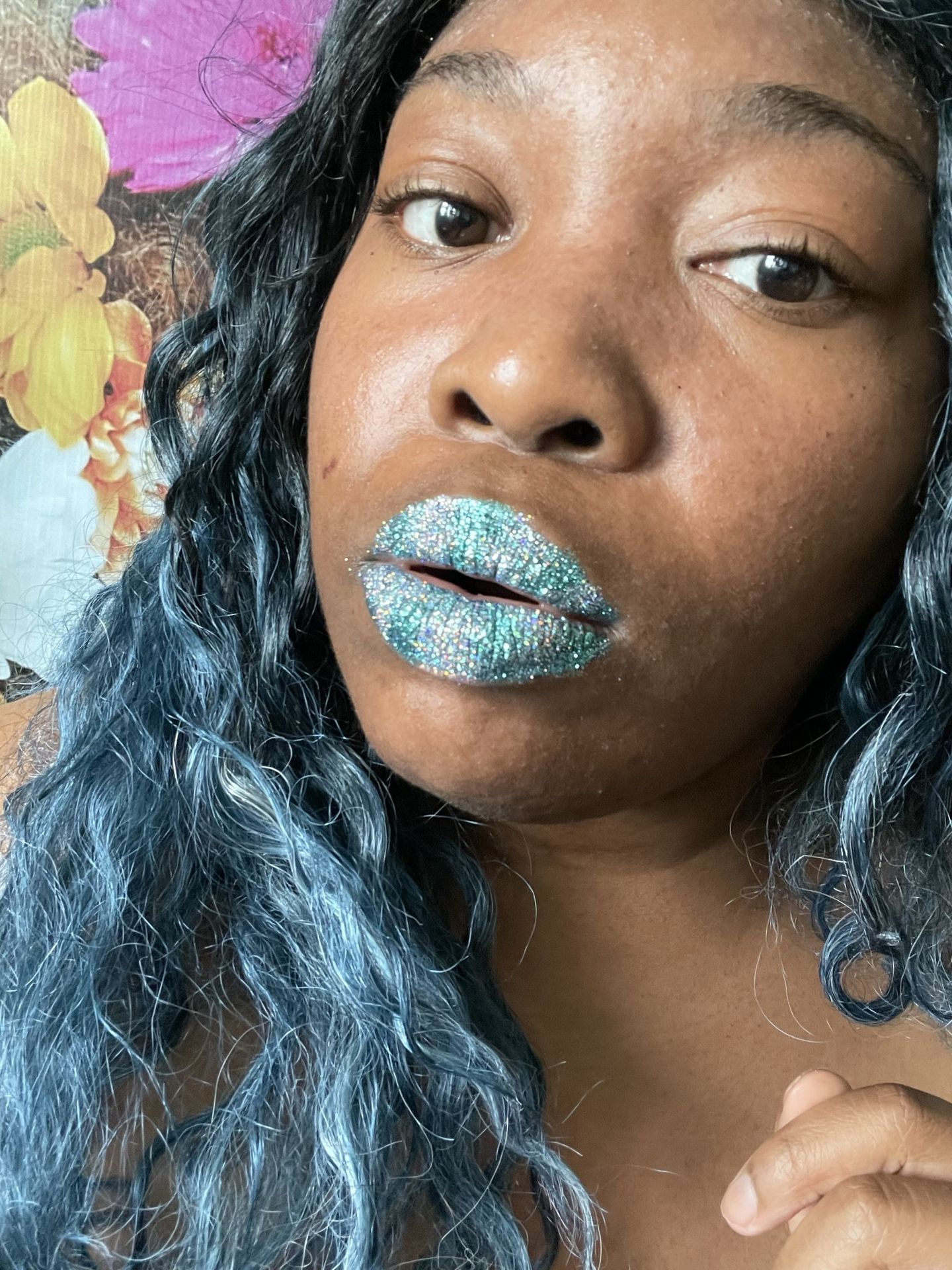 Woman with deep blue curls wearing sea-green glitter lips