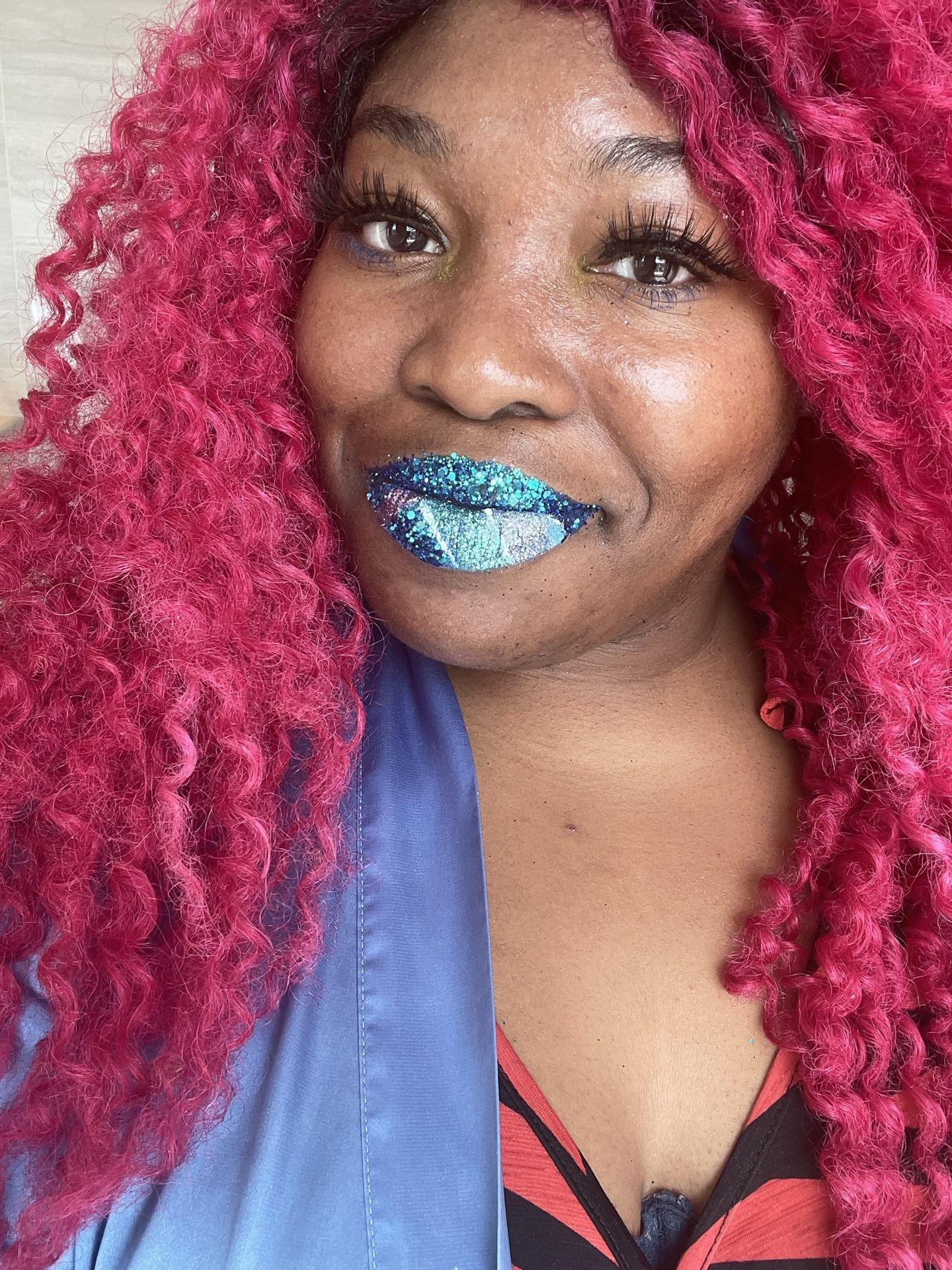 Woman smiling with ruby curls and frosted aqua lip gloss