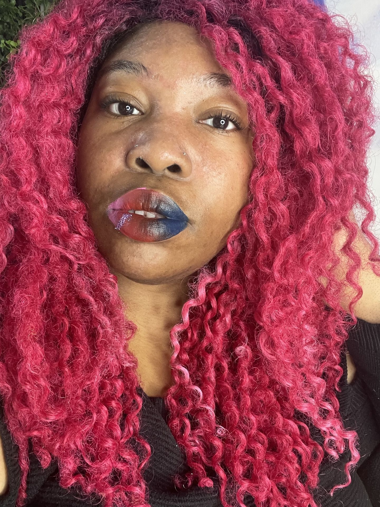 Woman with long pink curls wearing sheer coral gloss