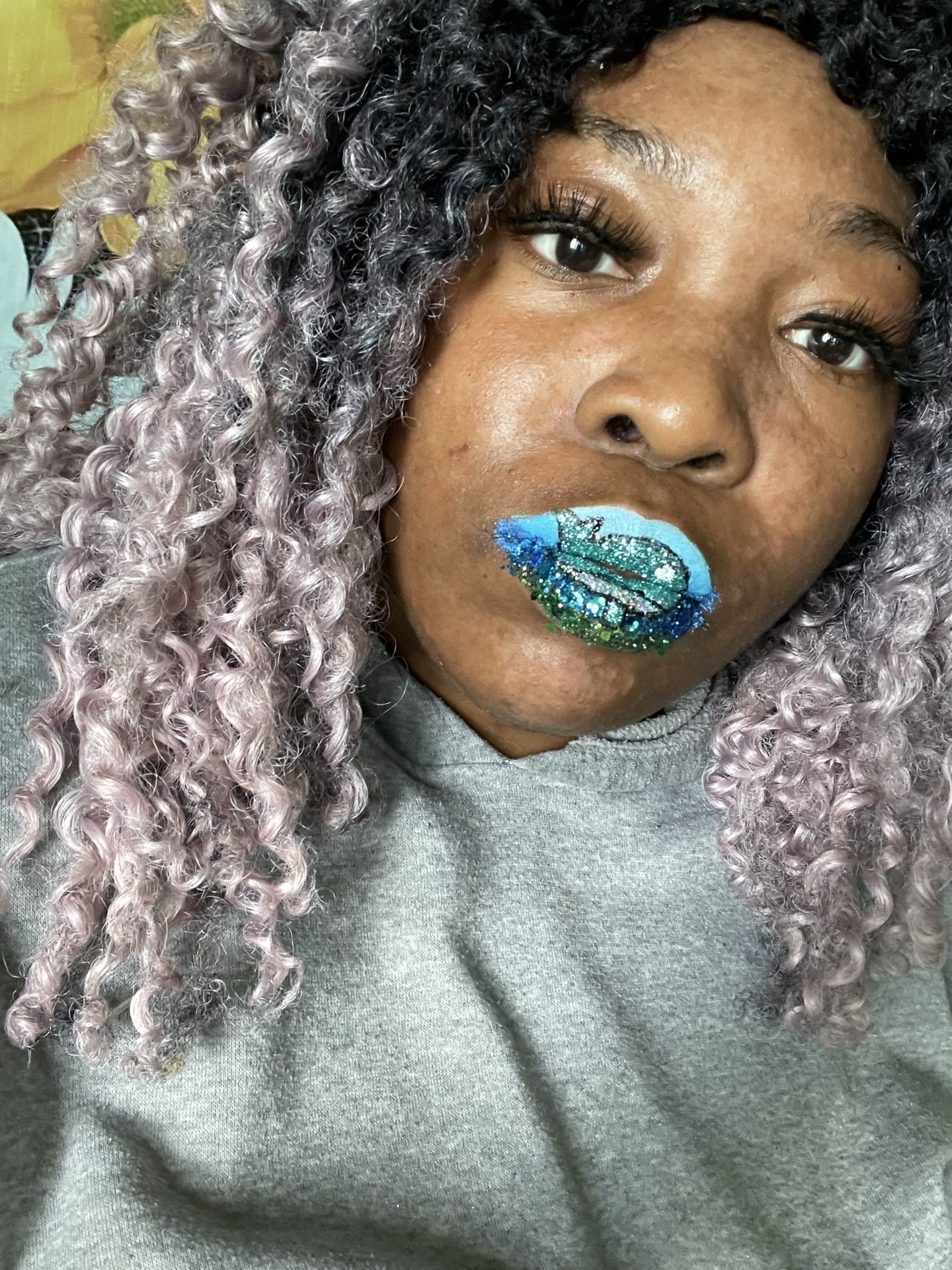 Woman with ash-blonde curls and emerald metallic lipstick